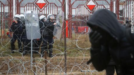 Polish servicemen are seen on the other side of barbed wire during clashes between migrants and Polish border guards at the Belarus-Poland border near Grodno, Belarus, on Tuesday, Nov. 16, 2021.