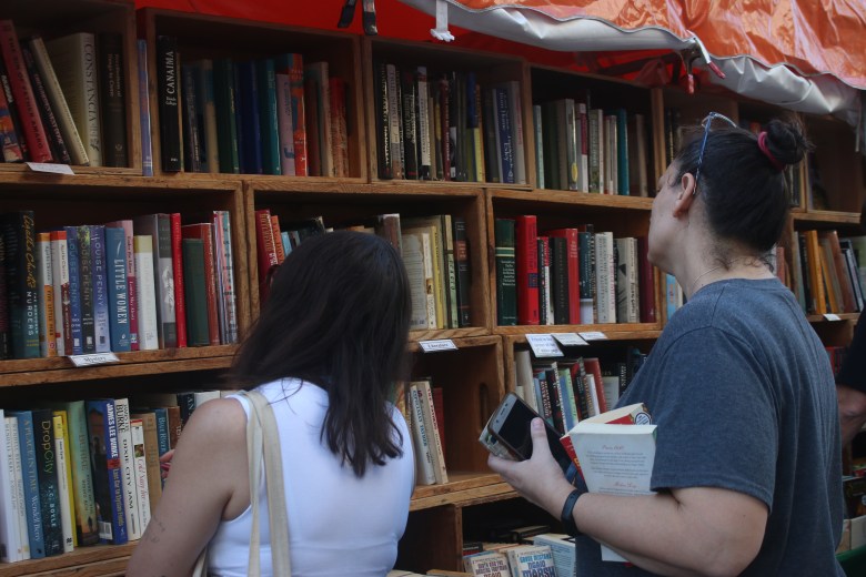 Visitors browse books at a vendor tent during the Street Fair at the Miami Book Fair on Sunday, Nov. 23, 2025. Photo by Béatrice Vallières for The Haitian Times.