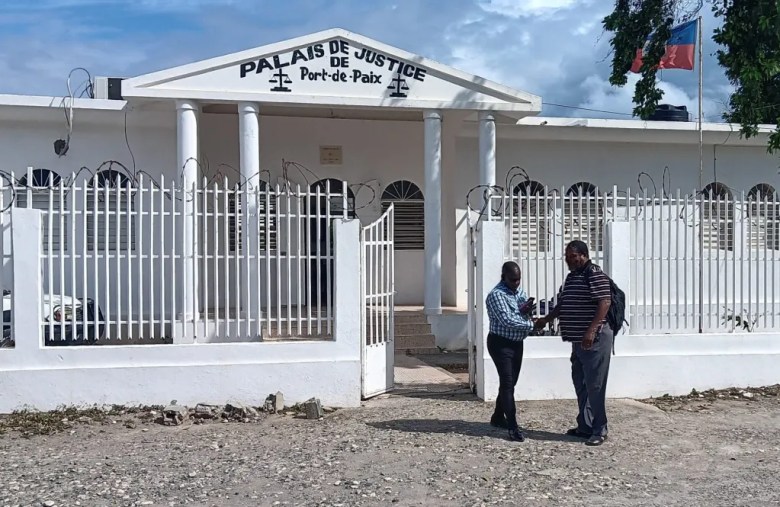 Two lawyers from the Port-de-Paix prosecutor’s office greet each other in front of the city’s courthouse on Thursday, March 25, 2026. Photo by Kervenson Martial/The Haitian Times