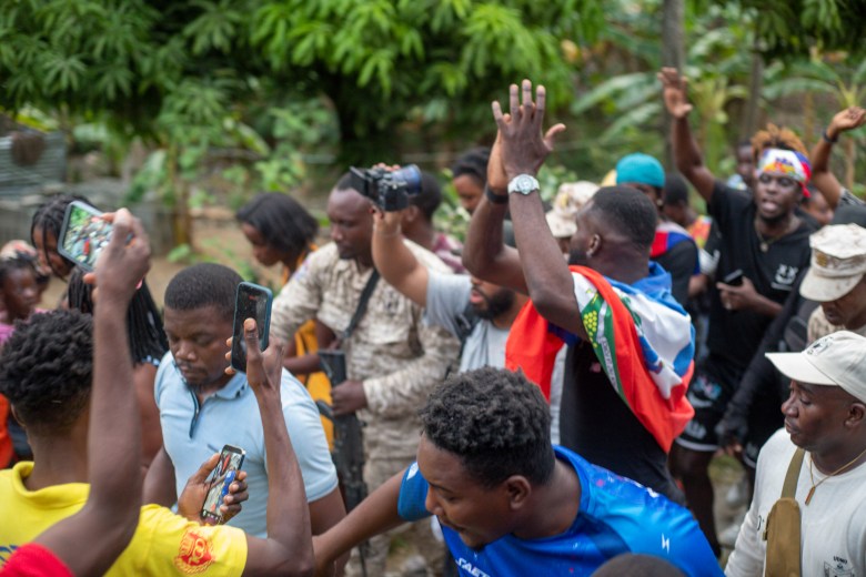 With the Haitian flag wrapped around his neck, Frantzdy Pierrot greets fans upon arriving in his hometown, Bas-Limbé, Haiti, on Friday, July 10, 2026. Photo by Ketlain Difficile for The Haitian Times.