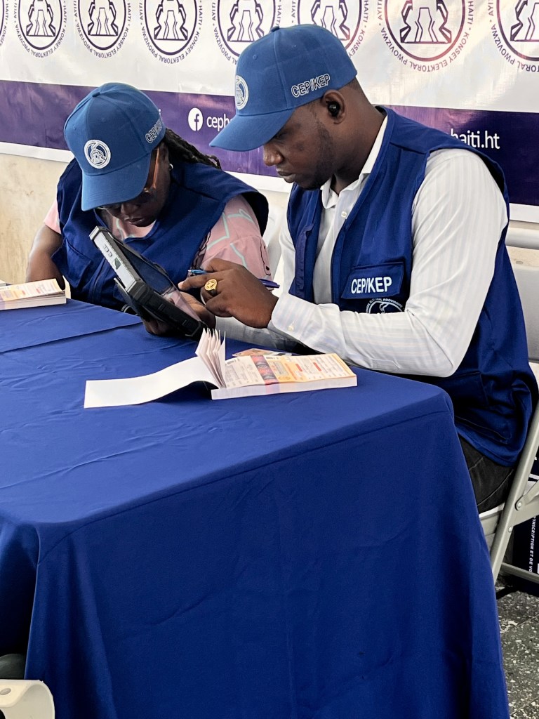 Two Provisional Electoral Council employees register voters at Lycée National de Pétion-Ville’s Registration and Voting Center during the launch of the process in the West Department on Thursday, July 30, 2026. Photo by Juhakenson Blaise/The Haitian Times.